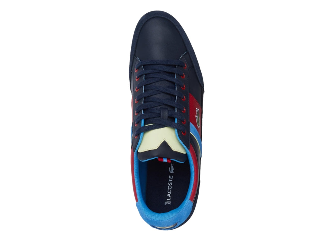 Tenis Lacoste azul marino con franjas laterales en rojo, azul y amarillo y logotipo del cocodrilo.