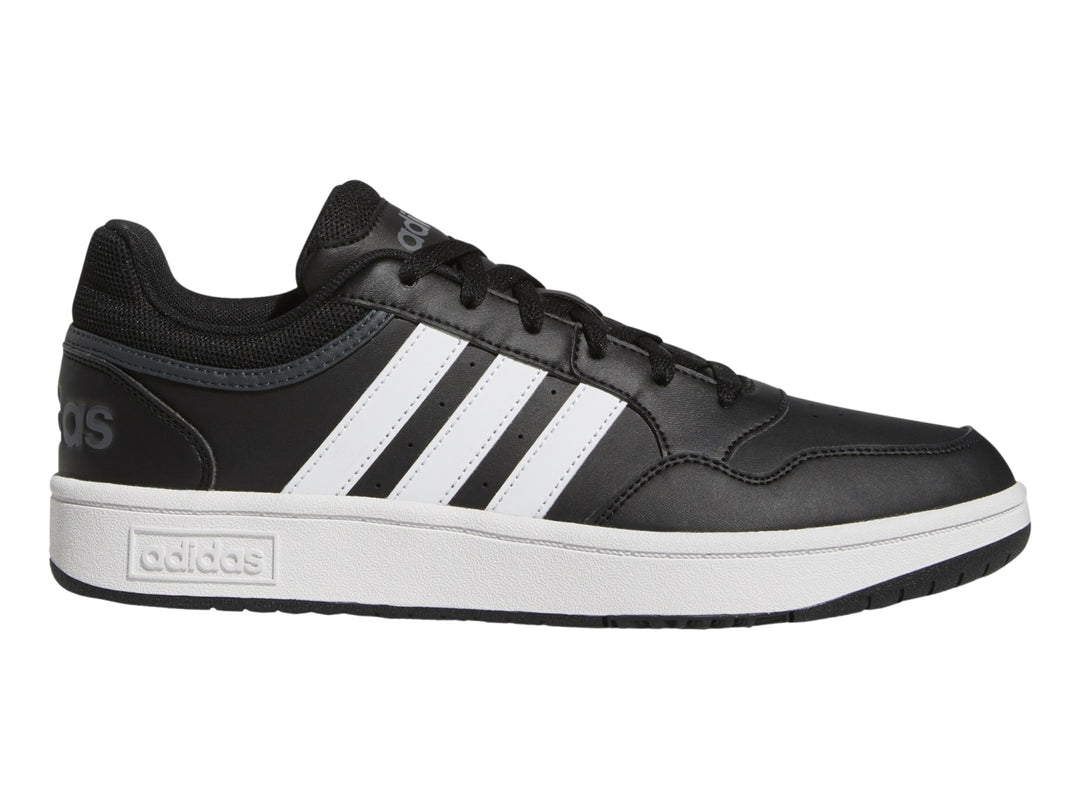 Tenis Adidas color negro con franjas blancas y suela blanca.