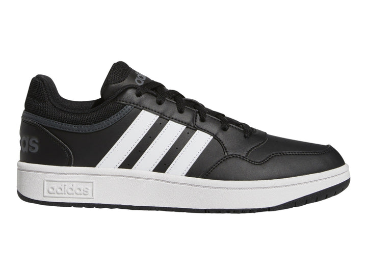 Tenis Adidas color negro con franjas blancas y suela blanca.