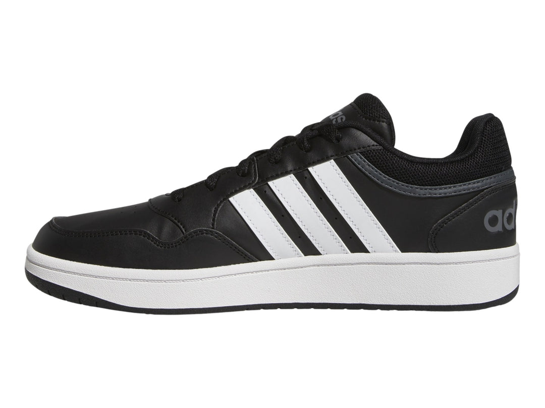 Tenis Adidas color negro con franjas blancas y suela blanca.