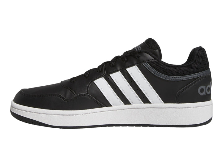 Tenis Adidas color negro con franjas blancas y suela blanca.