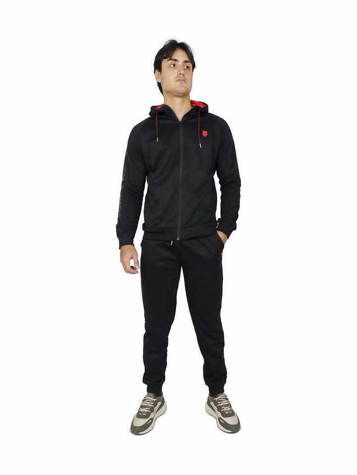 Hombre vistiendo pantalón deportivo negro K-Swiss con sudadera a juego sobre fondo blanco.