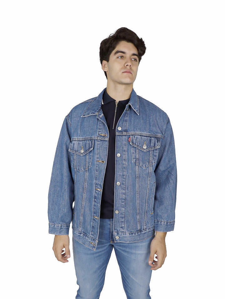 Hombre vistiendo una chaqueta de mezclilla azul claro de corte holgado y pantalones a juego.