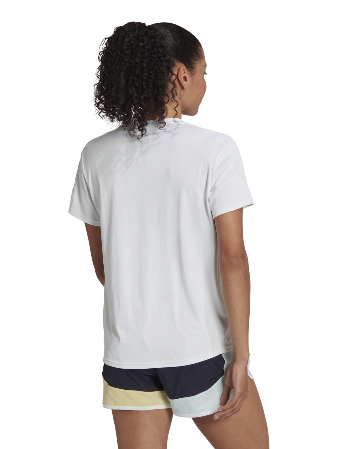 Mujer vistiendo una camiseta deportiva blanca de manga corta marca Adidas.