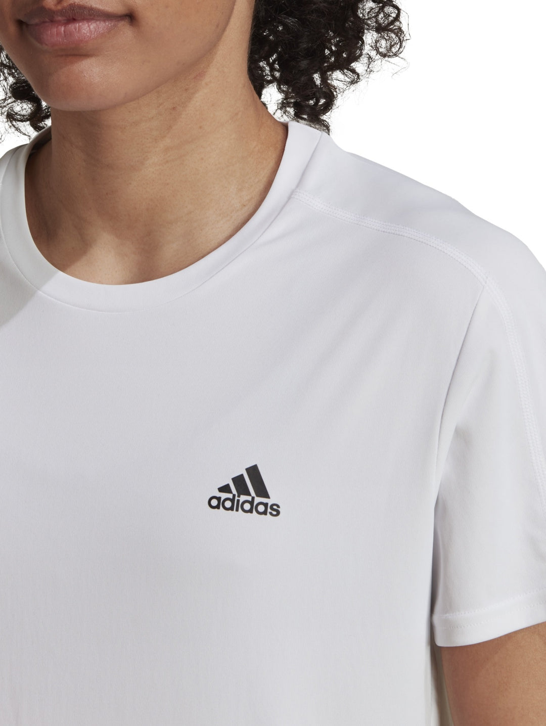 Mujer vistiendo una camiseta deportiva blanca de manga corta marca Adidas.