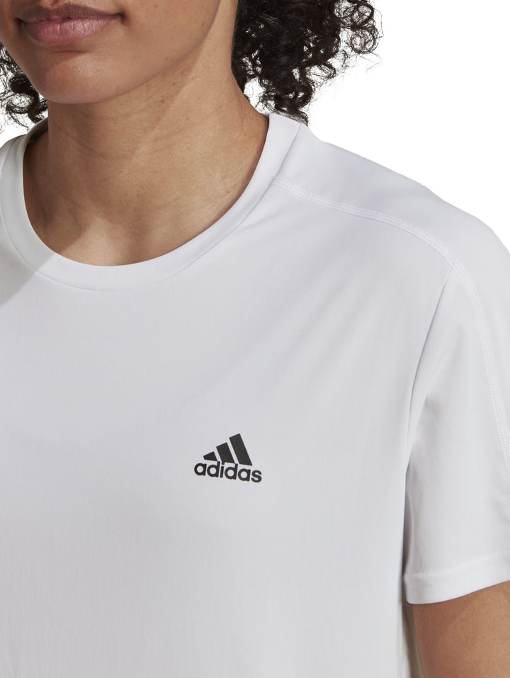Mujer vistiendo una camiseta deportiva blanca de manga corta marca Adidas.