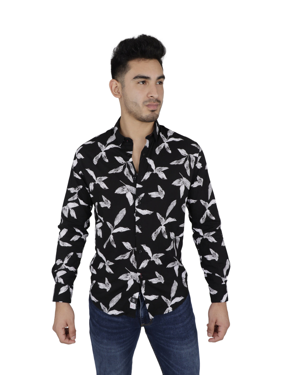 Hombre vistiendo camisa negra de manga larga con estampado de hojas blancas y pantalones vaqueros azules.