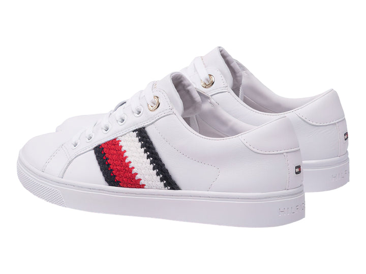 Tenis blancos Tommy Hilfiger con franjas laterales en rojo, blanco y azul marino y suela blanca.