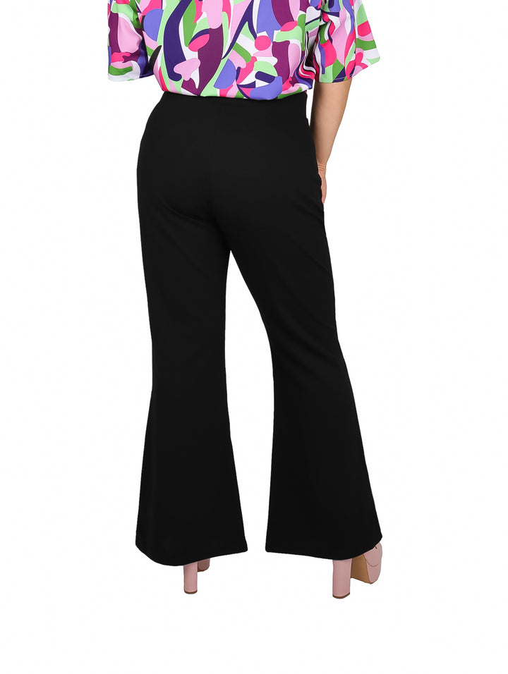 Mujer usando pantalón negro acampanado de talle alto con blusa multicolor y zapatos rosas.