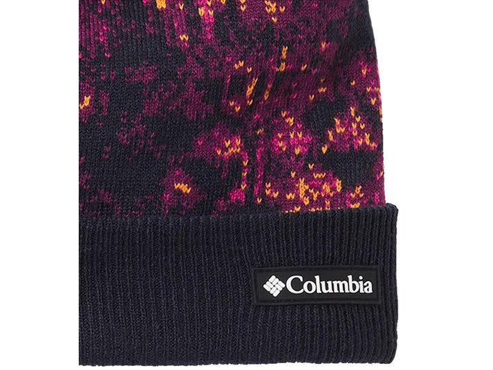 Gorro Columbia multicolor con estampado abstracto en tonos azul y rosa, rematado con un pompón rosa brillante.