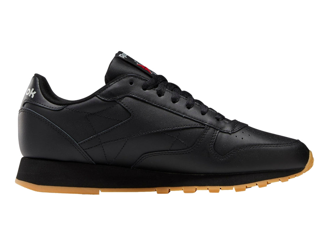 Tenis Reebok Classic Leather color negro con suela de goma marrón.