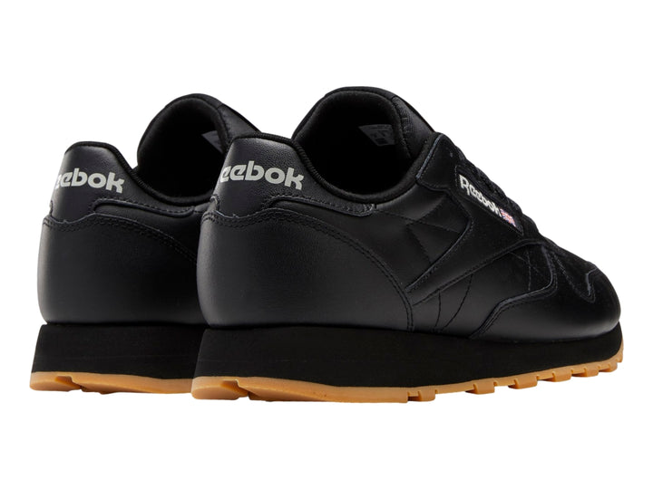 Tenis Reebok Classic Leather color negro con suela de goma marrón.