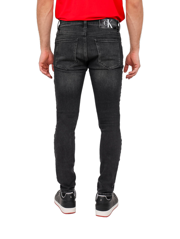 Hombre vistiendo pantalones jeans super skinny de color negro.