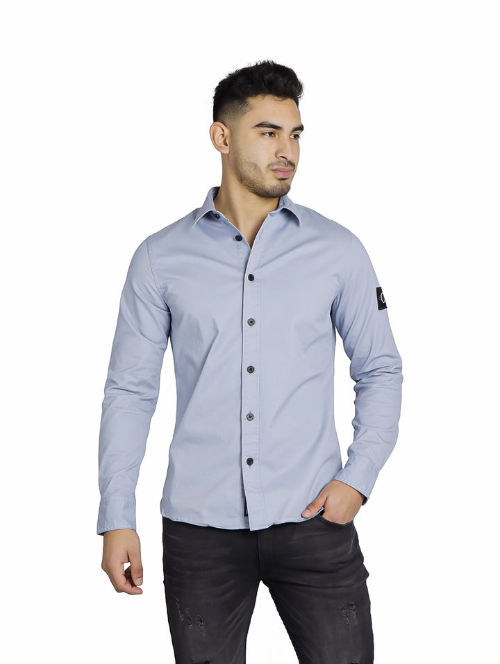 Hombre vistiendo una camisa Calvin Klein color Silver Sky de manga larga y cuello.