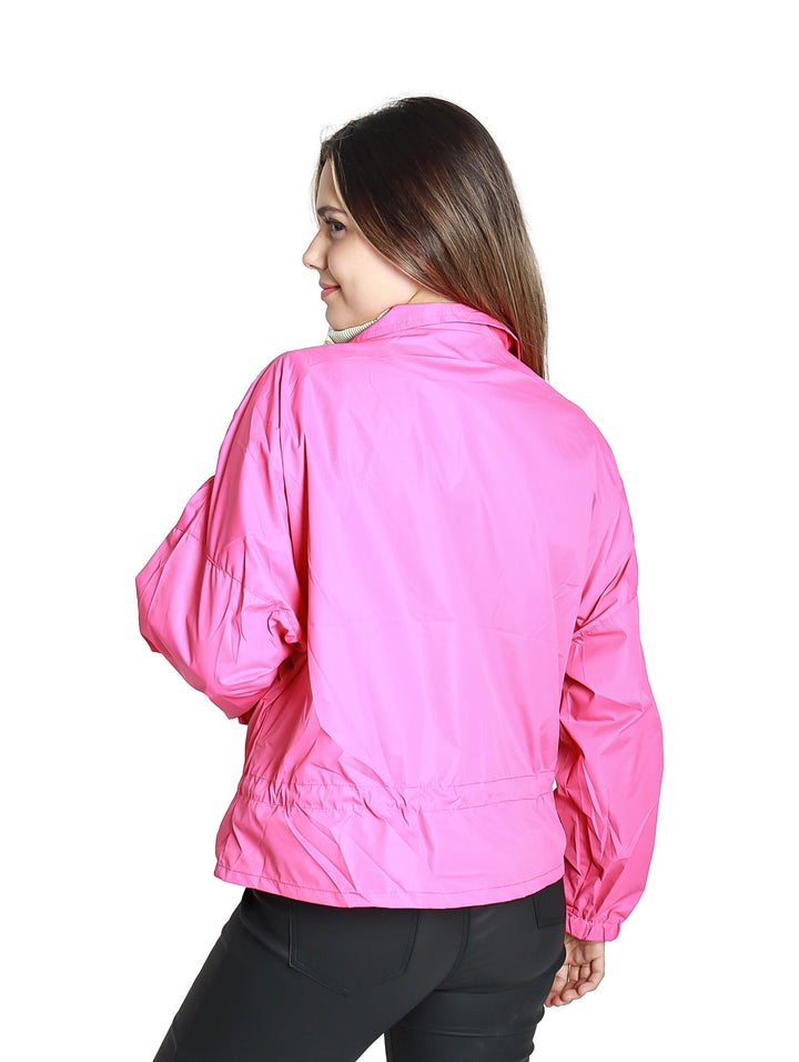 Mujer vistiendo una chamarra rompevientos de color fucsia con cierre frontal y ajuste en la cintura.