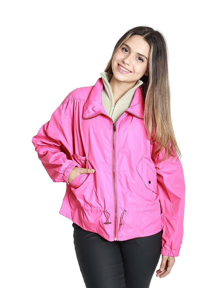 Mujer vistiendo una chamarra rompevientos de color fucsia con cierre frontal y ajuste en la cintura.
