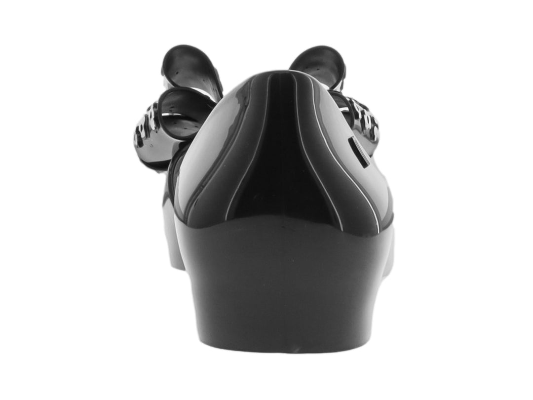 Zapato plano negro con moño decorativo con estampado de flores blancas.