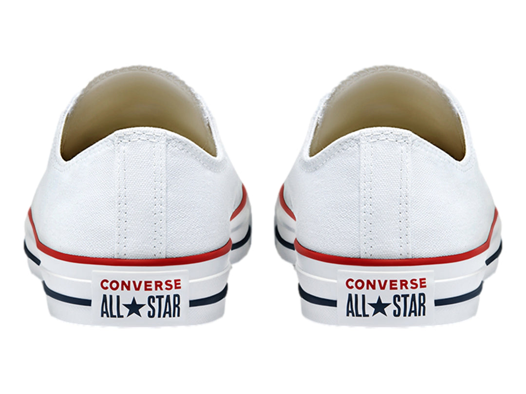 Tenis Converse blancos de lona con detalles en rojo y azul en la suela, diseño casual de corte bajo.