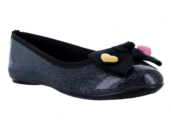 Zapato plano negro con acabado brillante y glitter, decorado con un moño negro y pequeños corazones amarillos y rosas.
