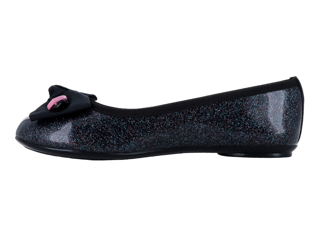 Zapato plano negro con acabado brillante y glitter, decorado con un moño negro y pequeños corazones amarillos y rosas.