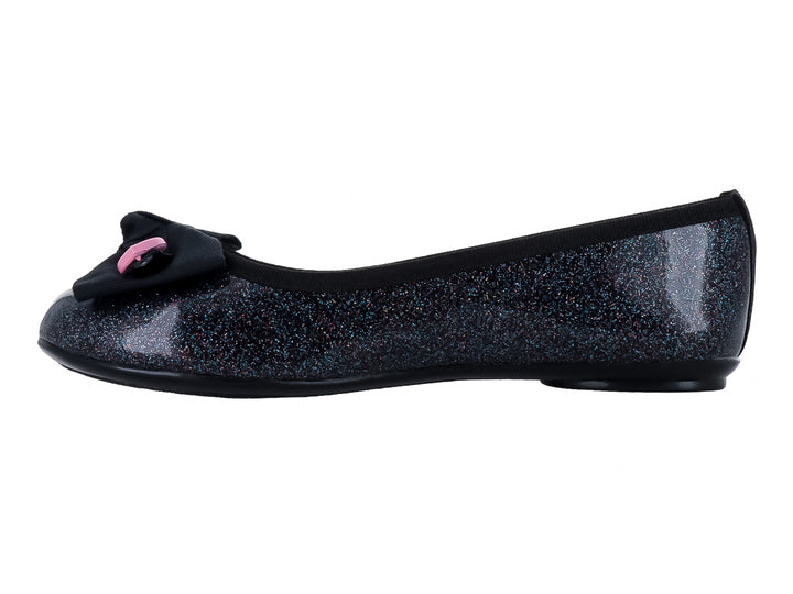 Zapato plano negro con acabado brillante y glitter, decorado con un moño negro y pequeños corazones amarillos y rosas.