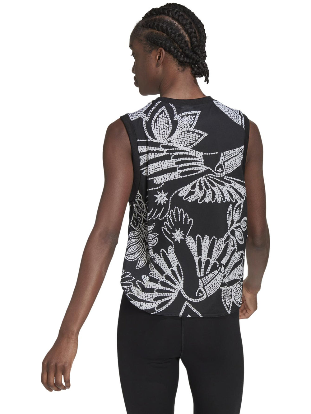 Mujer vistiendo una camiseta sin mangas Adidas negra con estampado floral blanco y logotipo naranja frontal.
