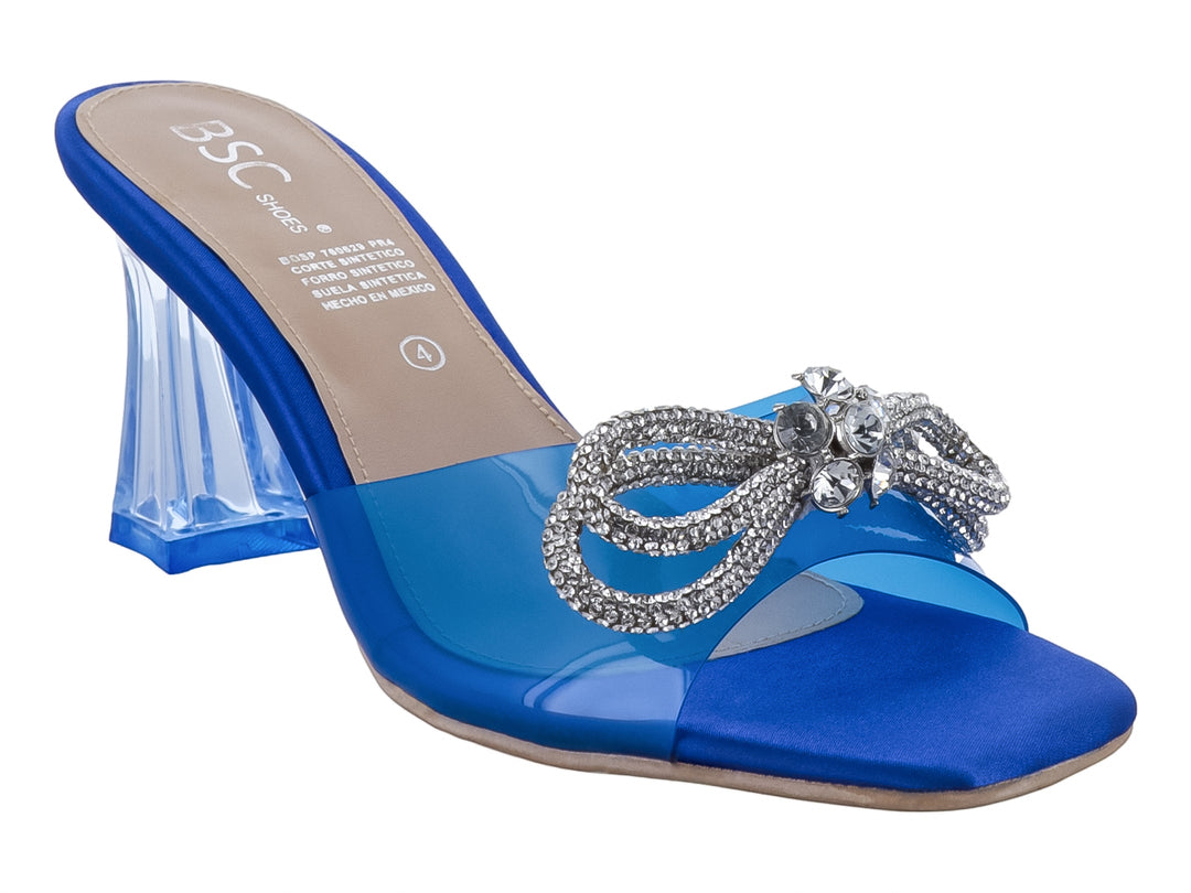 Sandalia azul de tacón bloque con tira transparente y moño decorativo de pedrería plateada.
