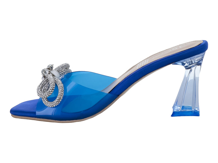 Sandalia azul de tacón bloque con tira transparente y moño decorativo de pedrería plateada.