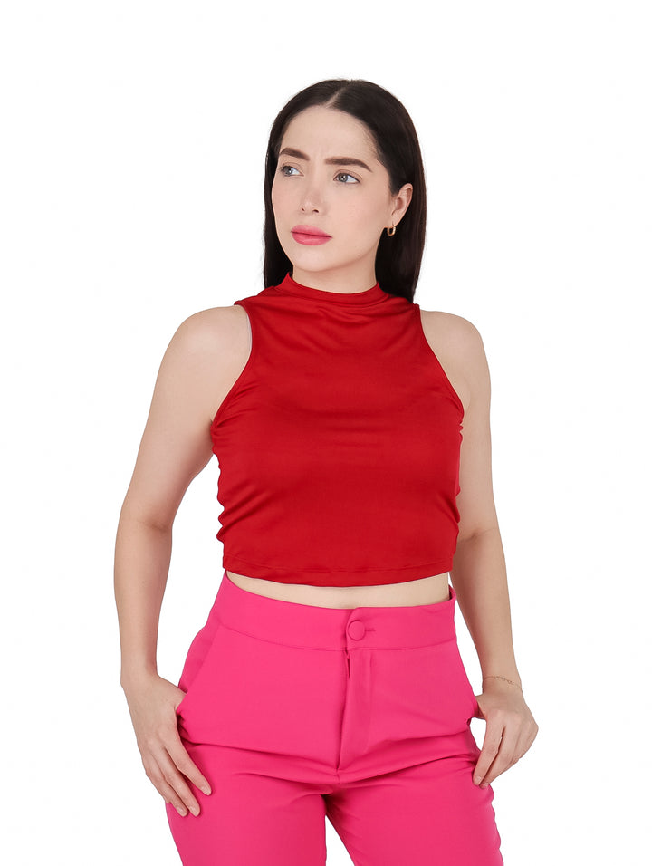 Mujer vistiendo una blusa roja sin mangas de cuello alto y pantalones rosas.