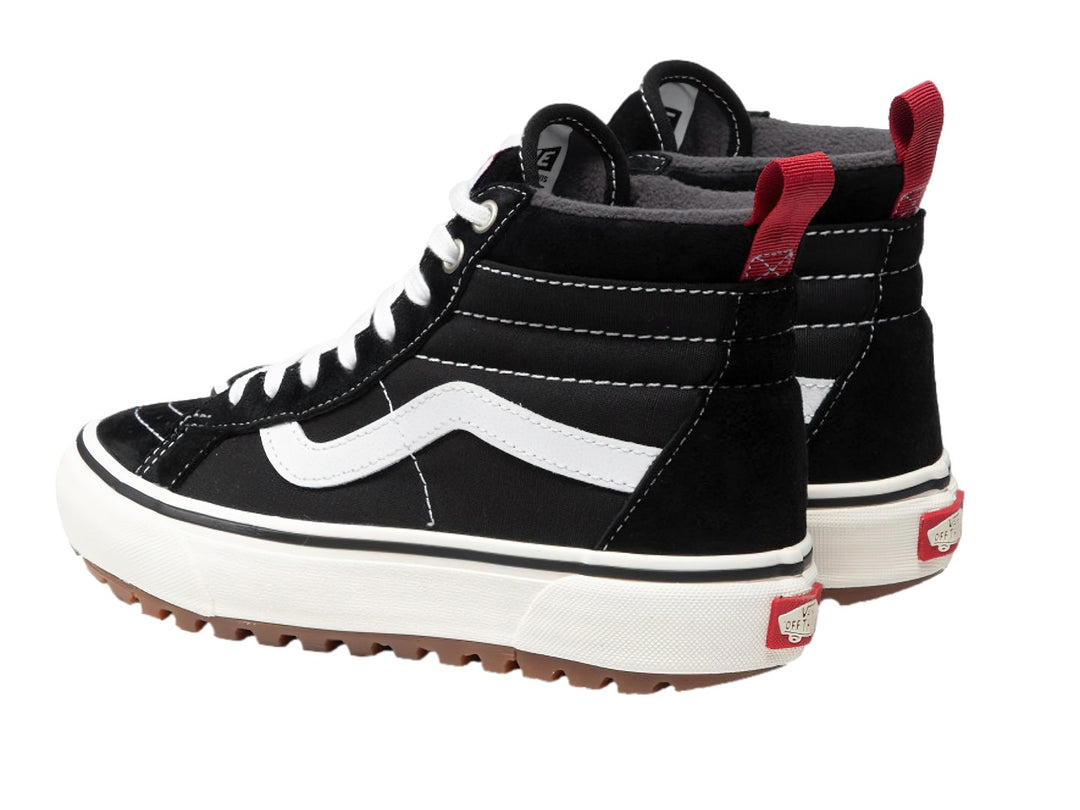 Tenis Vans Sk8-Hi negros con franja blanca lateral, suela blanca y lengüeta trasera roja.
