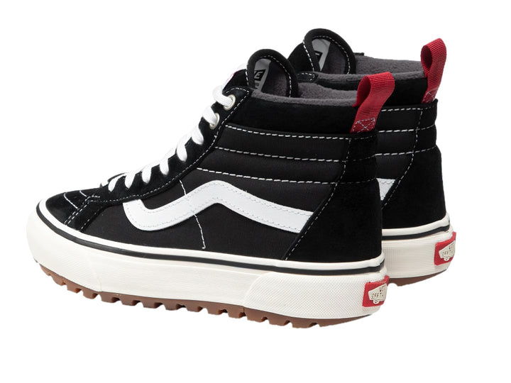 Tenis Vans Sk8-Hi negros con franja blanca lateral, suela blanca y lengüeta trasera roja.