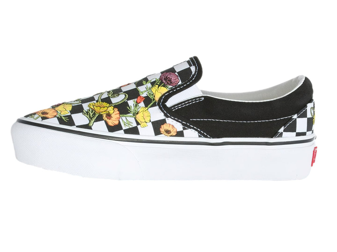 Tenis Vans Classic Slip-On negros con estampado de cuadros blancos y flores multicolores, suela blanca gruesa.