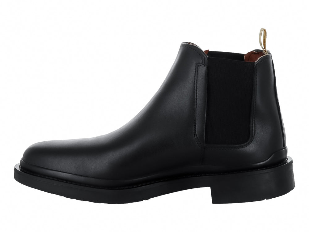 Bota Chelsea de color negro con suela gruesa y tirador beige en el talón.