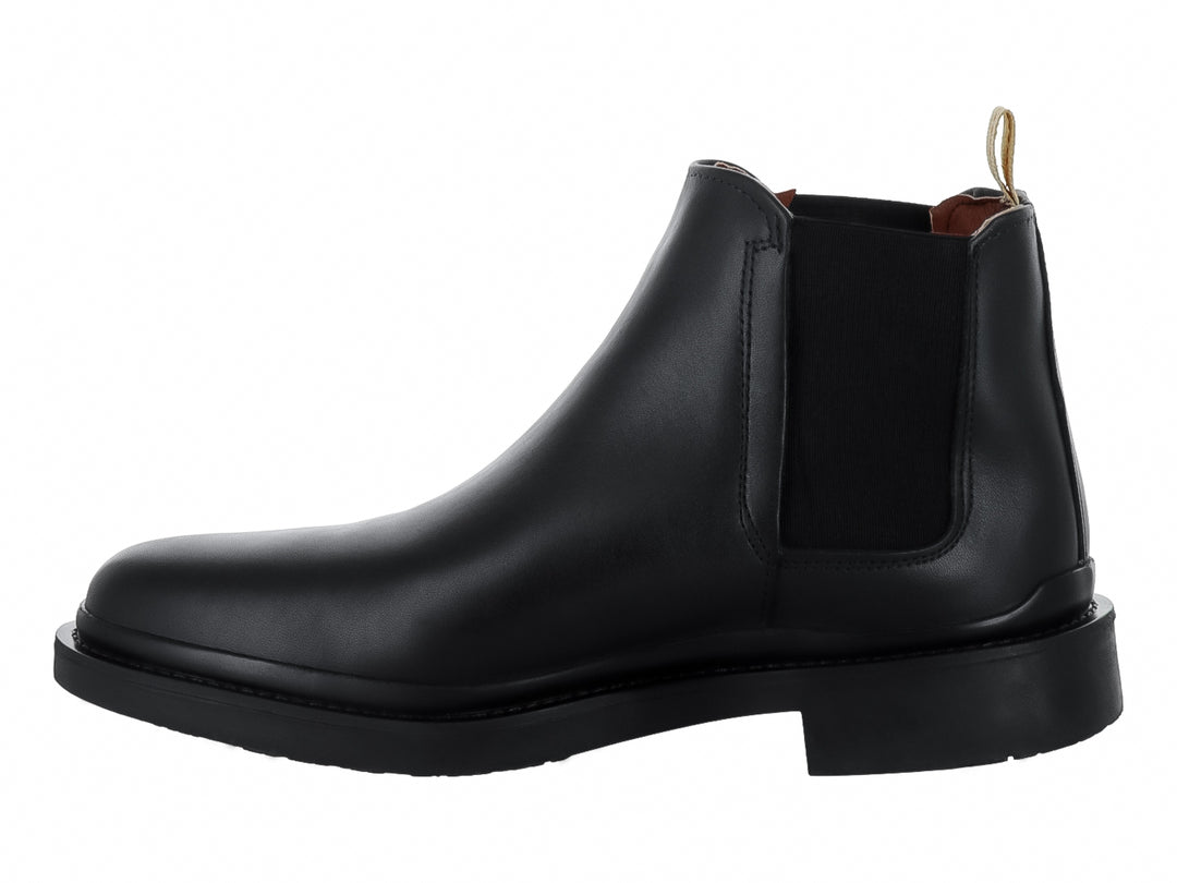 Bota Chelsea de color negro con suela gruesa y tirador beige en el talón.