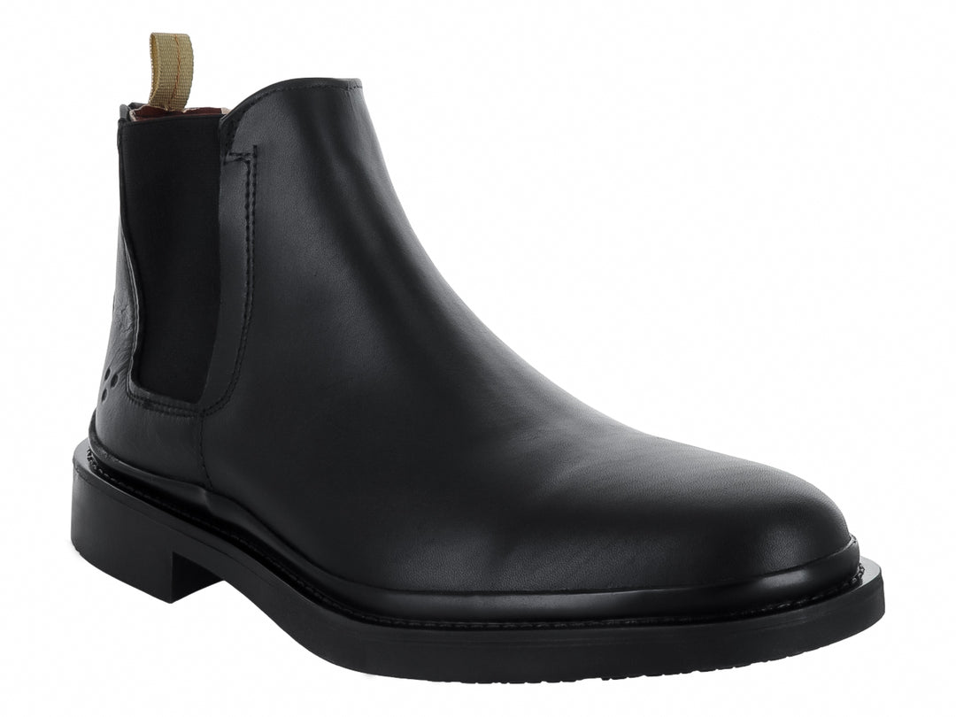 Bota Chelsea de color negro con suela gruesa y tirador beige en el talón.
