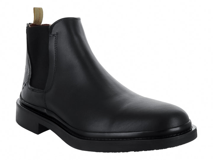 Bota Chelsea de color negro con suela gruesa y tirador beige en el talón.