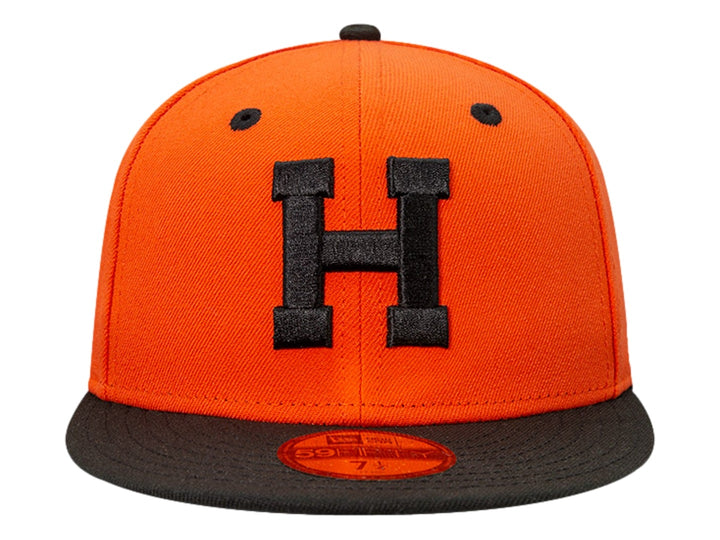 Gorra de béisbol New Era color naranja con visera plana negra y letra H bordada en negro al frente.
