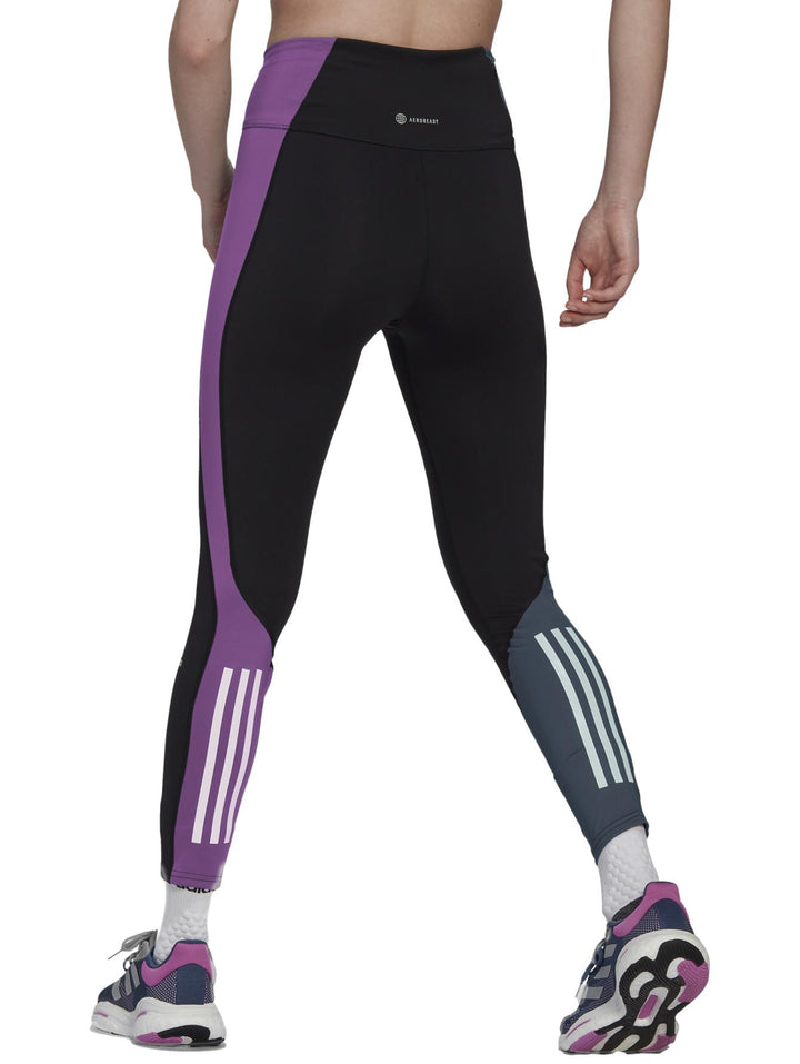Mallas deportivas Adidas negras con panel lateral morado y detalle gris en el tobillo.