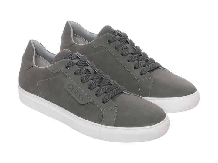 Tenis casuales Guess de color gris con suela blanca y agujetas a juego.