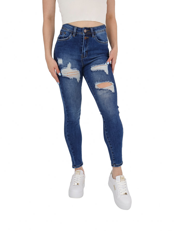 Mujer vistiendo pantalones jeans azules ajustados con detalles de destrucción en las piernas.