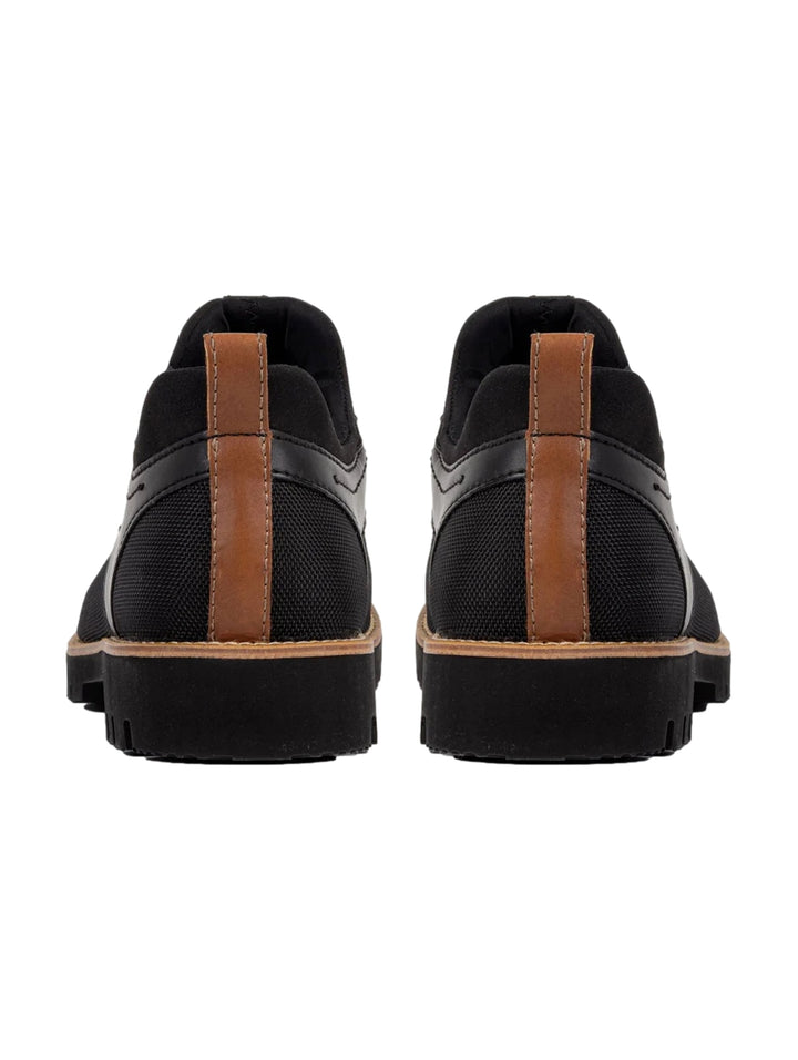 Zapato casual de lona color negro con suela gruesa y detalles en marrón, vista lateral.