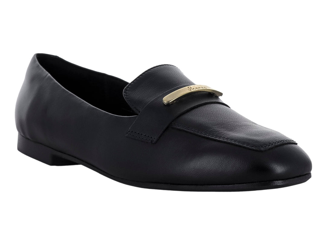 Zapato tipo mocasín de piel color negro con un adorno metálico dorado en la parte superior.