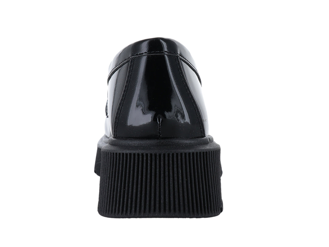 Mocasín negro brillante con suela de plataforma gruesa y adorno de cadena en la parte superior.