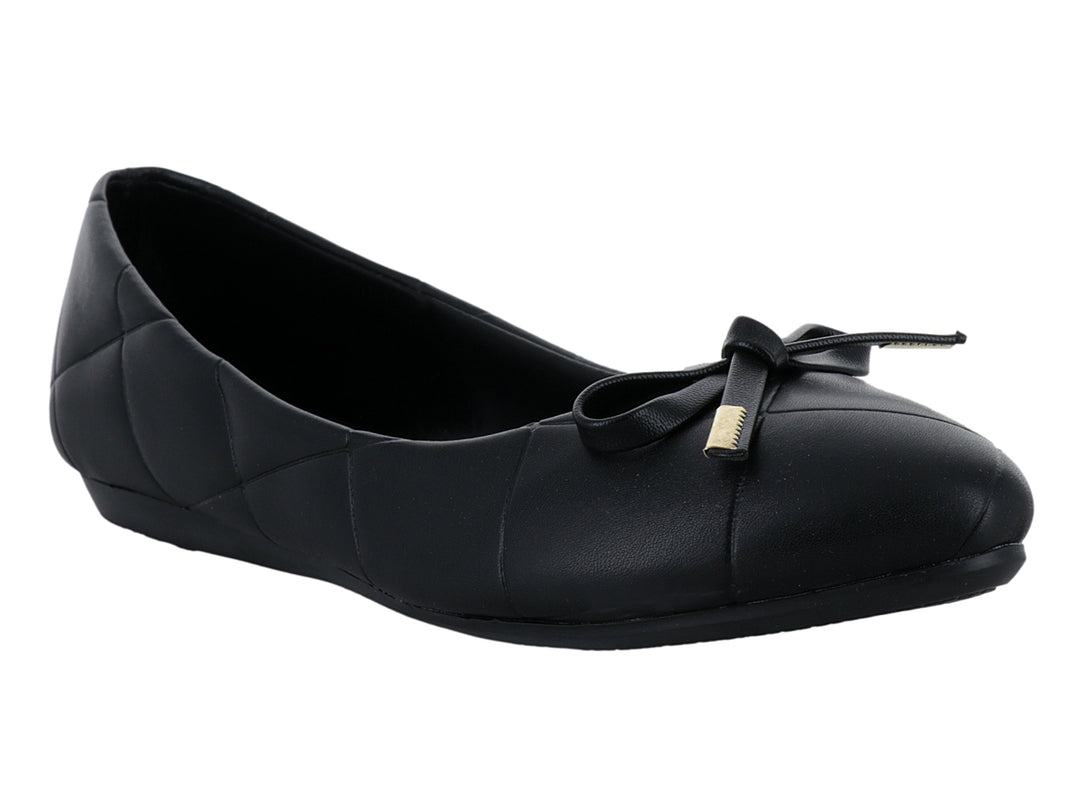 Zapato plano negro con diseño capitonado y moño con detalle dorado.