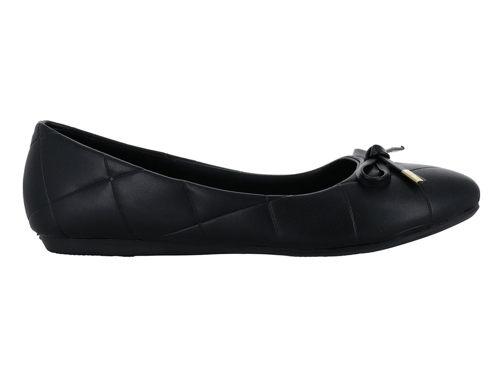 Zapato plano negro con diseño capitonado y moño con detalle dorado.