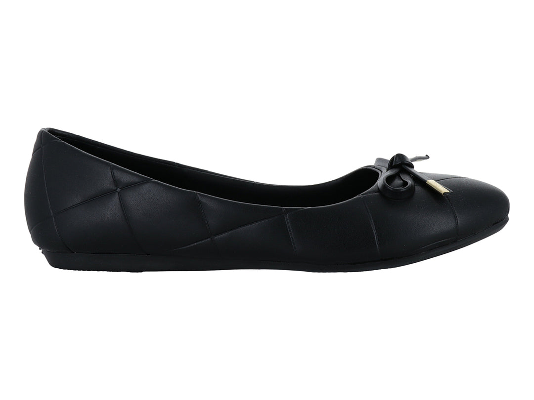 Zapato plano negro con diseño capitonado y moño con detalle dorado.