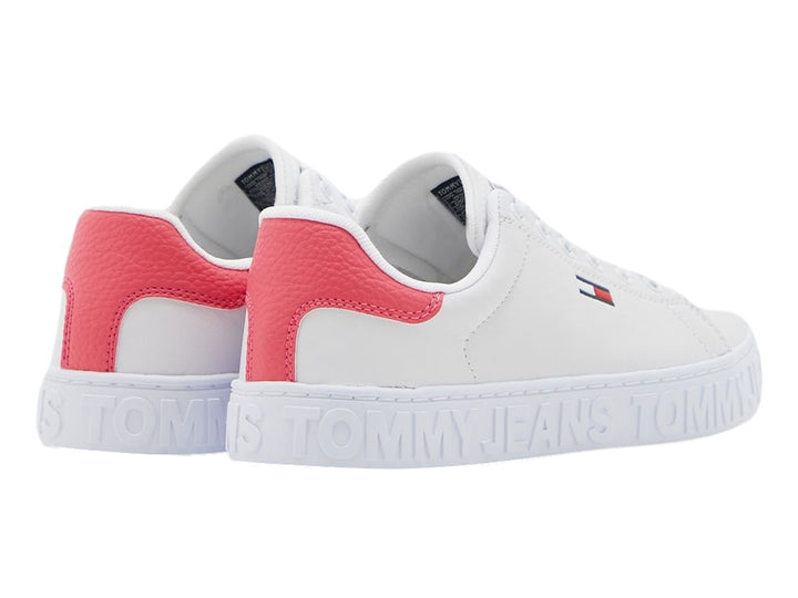 Tenis blancos Tommy Hilfiger con detalle rosa en el talón y suela con texto Tommy Jeans en relieve.