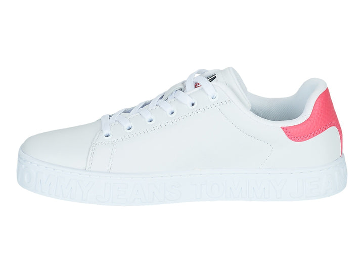 Tenis blancos Tommy Hilfiger con detalle rosa en el talón y suela con texto Tommy Jeans en relieve.