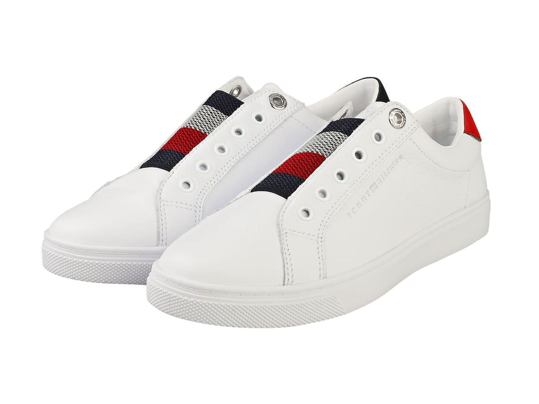 Tenis Tommy Hilfiger blancos estilo slip-on con banda elástica tricolor y detalle rojo en el talón.