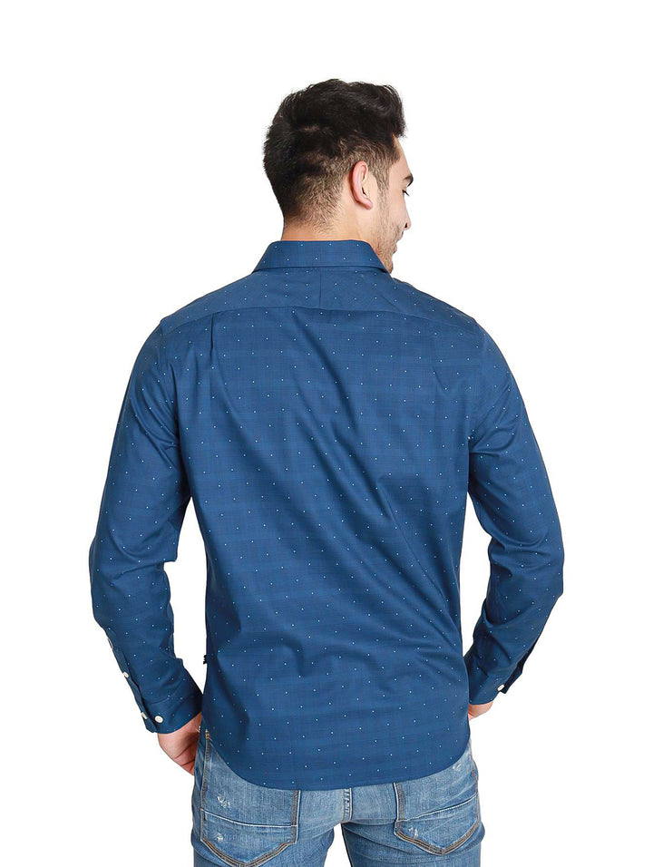 Hombre vistiendo una camisa azul marino de manga larga con pequeños puntos blancos.